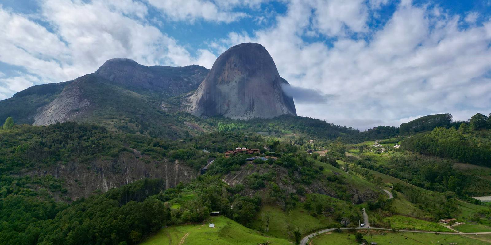 Pedra Azul vista do alto em Domingos Martins, com estrada sinuosa entre pastos e mata na região serrana do Espírito Santo